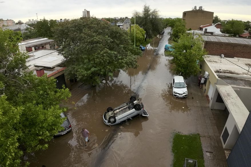 A flipped vehicle sits in flood waters after a storm in Bahia Blanca, Argentina, Friday, March 7, 2025. (AP Photo/Juan Sebastian Lobos)