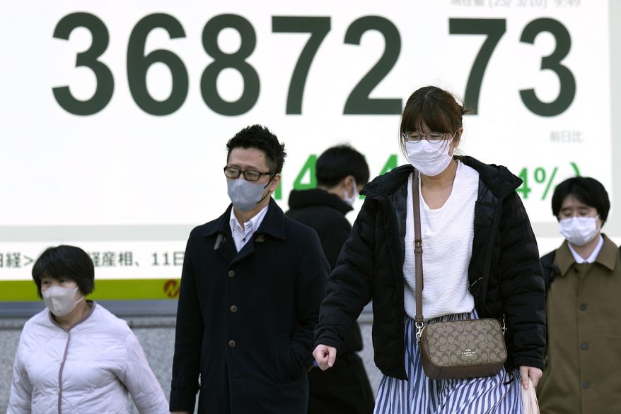 People walk in front of an electronic stock board showing Japan's Nikkei index at a securities firm Monday, March 10, 2025, in Tokyo. (AP Photo/Eugene Hoshiko)