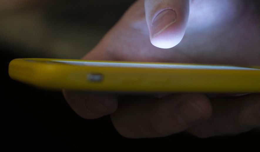 FILE - A man uses a cell phone in New Orleans on Aug. 11, 2019. (AP Photo/Jenny Kane, File)