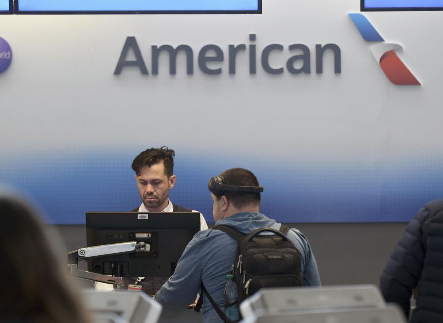 An American Airlines employee checks in a passenger at Denver International Airport on Friday, March 14, 2025, in Denver. (AP Photo/ Thomas Peipert)