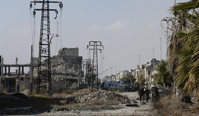 Syrian army soldiers walk next to damaged electricity transmission towers on their way back from the frontline of fighting, in Karam al-Tarab neighborhood of Aleppo, Syria, Dec. 4, 2016. (AP Photo/Hassan Ammar, File)