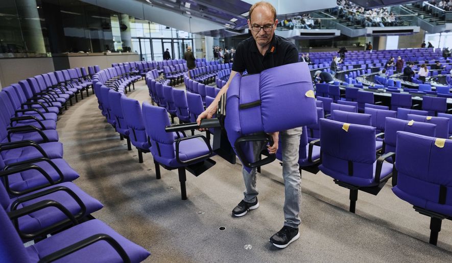 A worker removes a seat during the set-up for the new seating of the federal parliament Bundestag at the Reichstag building in Berlin, Wednesday, March 19, 2025. (AP Photo/Markus Schreiber)