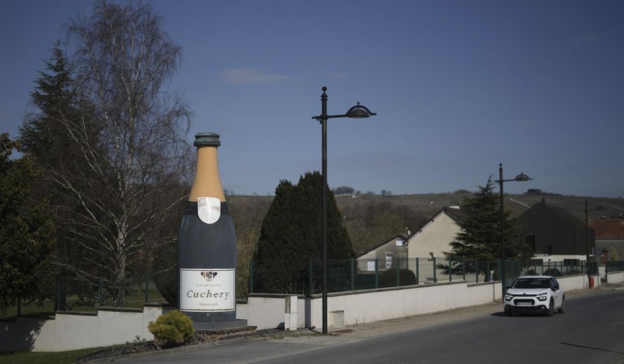 A giant plastic champagne bottle is seen at the entrance of Cuchery, eastern France, Monday, March 17, 2025. (AP Photo/Thibault Camus)