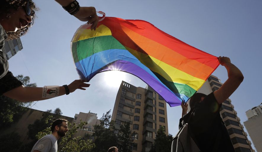 FILE - Activists from the Lesbian, Gay, Bisexual, and Transgender (LGBTQ) community in Lebanon shout slogans and hold up a rainbow demanding rights during a protest in Beirut, Lebanon, June 27, 2020. (AP Photo/Hassan Ammar, File)