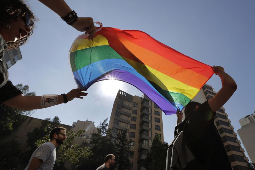 FILE - Activists from the Lesbian, Gay, Bisexual, and Transgender (LGBTQ) community in Lebanon shout slogans and hold up a rainbow demanding rights during a protest in Beirut, Lebanon, June 27, 2020. (AP Photo/Hassan Ammar, File)