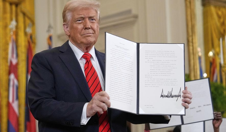 President Donald Trump holds up a signed executive order at an education event in the East Room of the White House in Washington, Thursday, March 20, 2025. (AP Photo/Ben Curtis)