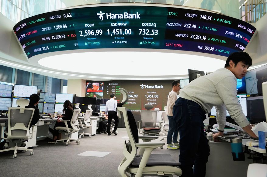 FILE - Currency traders work near a screen showing the Korea Composite Stock Price Index (KOSPI), top center left, and the foreign exchange rate between U.S. dollar and South Korean won, top center, at the foreign exchange dealing room of the KEB Hana Bank headquarters in Seoul, South Korea, Thursday, March 13, 2025. (AP Photo/Ahn Young-joon, File)