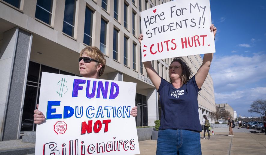 High School teacher June Kelly, left, and SJ Marcotte, right, who teaches business leadership, both with a group of educators from Vermont, hold signs in support of the Department of Education, Thursday, March 20, 2025, outside the department in Washington. (AP Photo/Jacquelyn Martin) ** FILE **