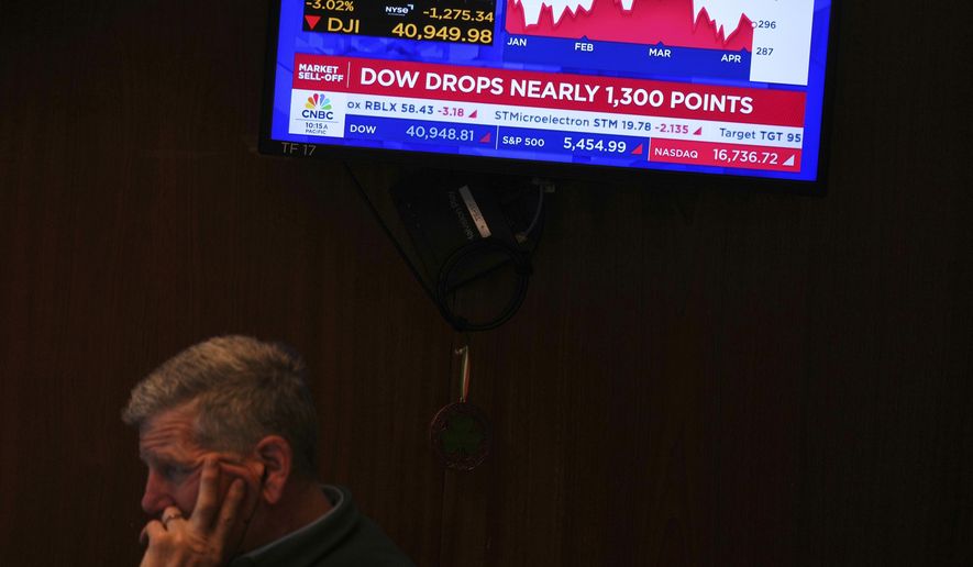 A screen displays financial news as traders work on the floor at the New York Stock Exchange in New York, Thursday, April 3, 2025. (AP Photo/Seth Wenig)