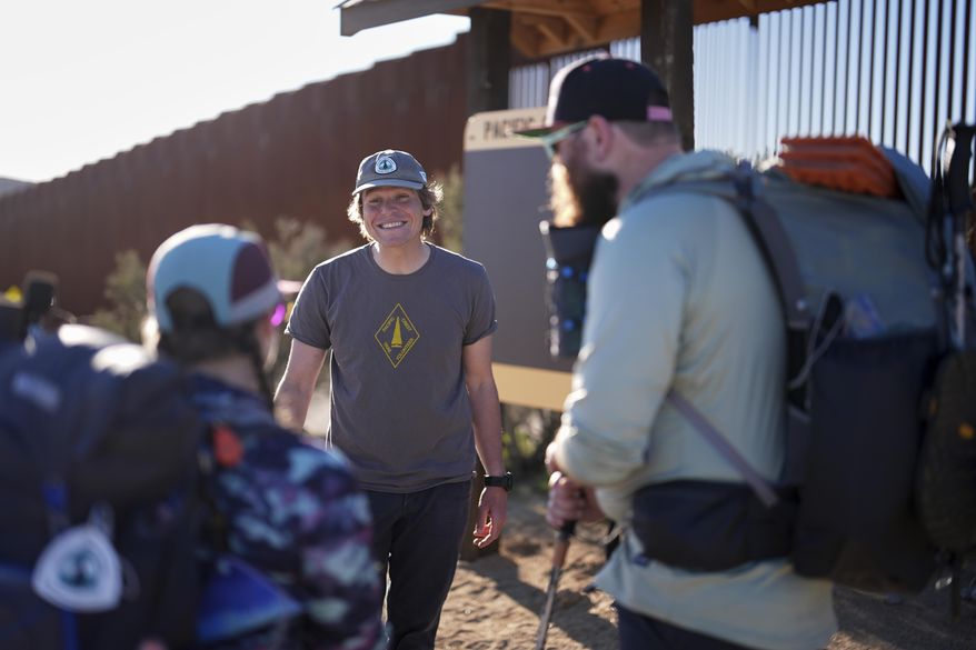 Eric Kipperman, one of the Pacific Crest Trail Association's experienced guides known as "crest runners", center, speaks to hikers Joshua Suran and Laura Flocchini as they get ready to begin their hike at the southern terminus of the Pacific Crest Trail near the border with Mexico, Monday, March 24, 2025, near Campo, Calif. (AP Photo/Gregory Bull)