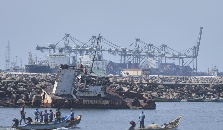 Local fishermen on their boats sail past huge cranes loading containers on to ships at a port in Chennai, India, Tuesday, April 8, 2025. (AP Photo/R. Parthibhan)
