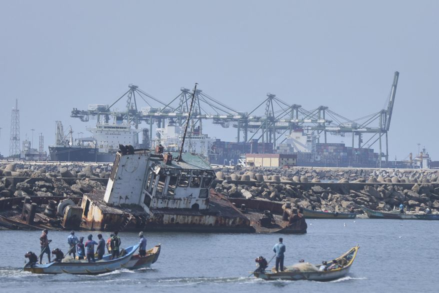Local fishermen on their boats sail past huge cranes loading containers on to ships at a port in Chennai, India, Tuesday, April 8, 2025. (AP Photo/R. Parthibhan)