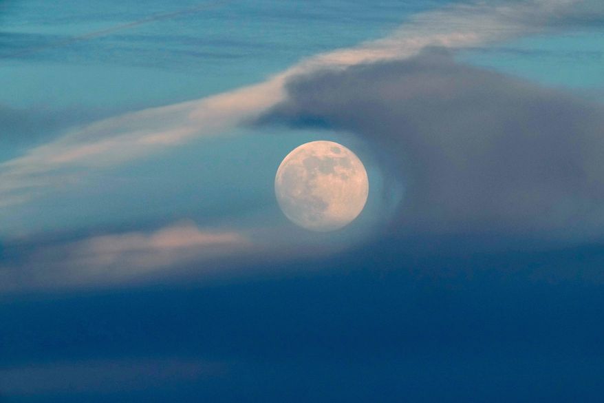 A full moon rises above the clouds at sunset in Lisbon, Saturday, Dec. 14, 2024. (AP Photo/Armando Franca, File)