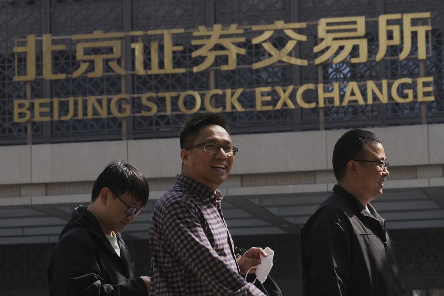 People walk by Beijing Stock Exchange on the Financial Street, in Beijing, Thursday, April 10, 2025. (AP Photo/Andy Wong)