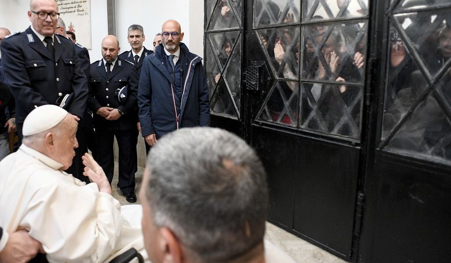 Pope Francis waves at inmates behind a closed gate during his visit to the Regina Coeli penitentiary in Rome on Holy Thursday, Thursday, April 17, 2025. (Vatican Media via AP, HO)