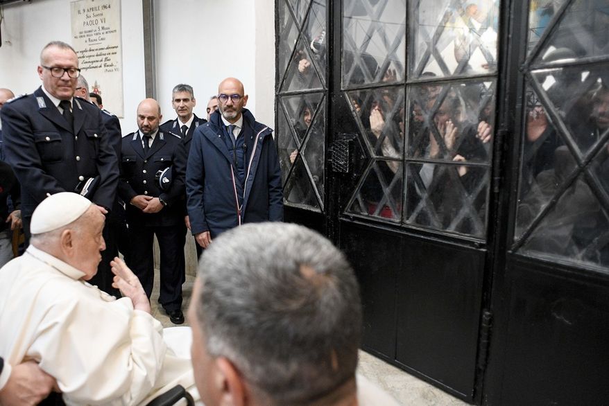 Pope Francis waves at inmates behind a closed gate during his visit to the Regina Coeli penitentiary in Rome on Holy Thursday, Thursday, April 17, 2025. (Vatican Media via AP, HO)