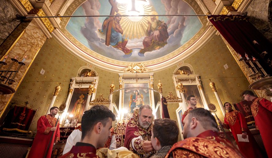 A boy receives the holy communion from Iraq-born Armenian church Archbishop Datev Hagopian during the Orthodox Easter service at the Armenian cathedral in Bucharest, Romania, Saturday, April 19, 2025. (AP Photo/Andreea Alexandru)