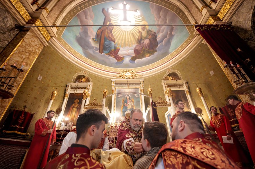 A boy receives the holy communion from Iraq-born Armenian church Archbishop Datev Hagopian during the Orthodox Easter service at the Armenian cathedral in Bucharest, Romania, Saturday, April 19, 2025. (AP Photo/Andreea Alexandru)