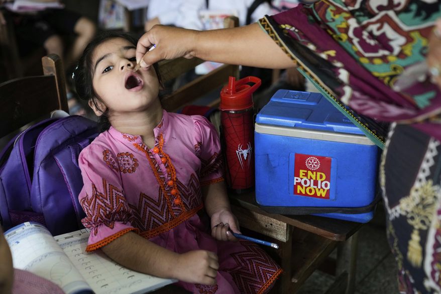 A health worker administers a polio vaccine to a child in a school in Lahore, Pakistan Monday, April 21, 2025. (AP Photo/K.M. Chaudary)