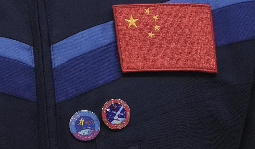 A Chinese national flag and pins showing the Tiangong space station are displayed on a uniform of Chinese astronaut for the upcoming Shenzhou-20 mission during a meeting with media at the Jiuquan Satellite Launch Center in northwest China, Wednesday, April 23, 2025. (AP Photo/Andy Wong)