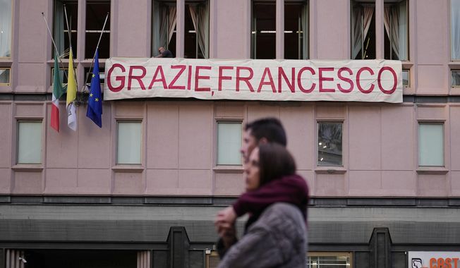 People set up a banner on a building near the Santa Maria Maggiore Basilica, where the late Pope Francis will be buried, in Rome, Thursday, April 24, 2025. (AP Photo/Andreea Alexandru)