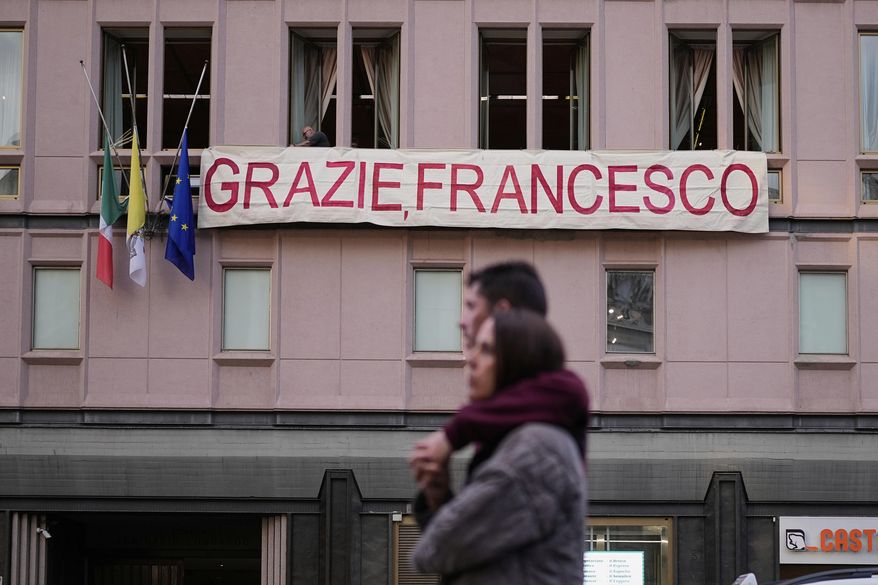 People set up a banner on a building near the Santa Maria Maggiore Basilica, where the late Pope Francis will be buried, in Rome, Thursday, April 24, 2025. (AP Photo/Andreea Alexandru)