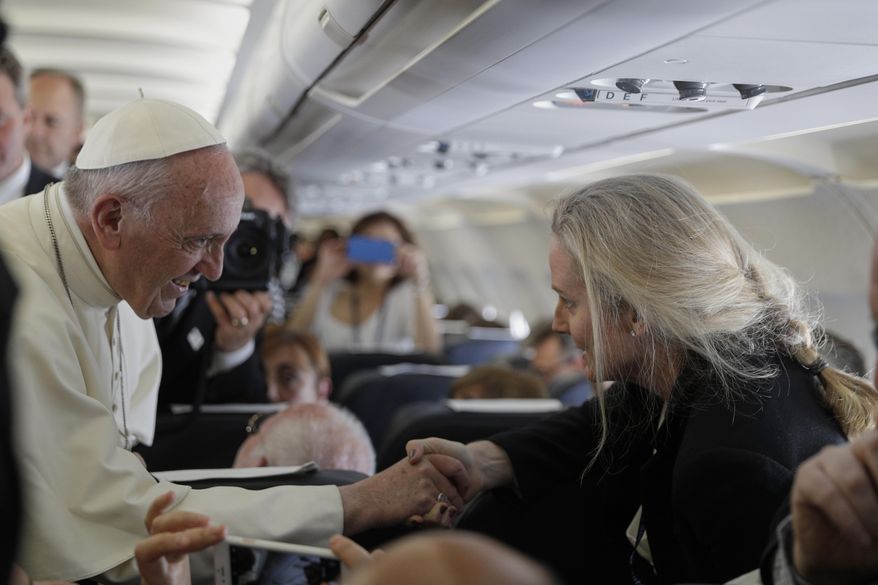 Pope Francis shakes hands with Associated Press correspondent Nicole Winfield aboard his plane bound for Fatima, Portugal, on May 12, 2017. (AP Photo/Alessandra Tarantino)