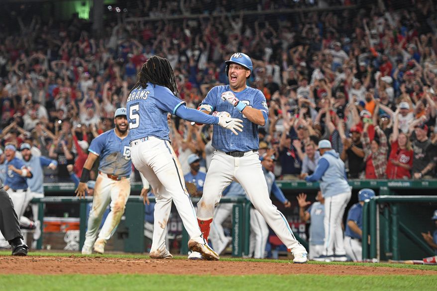 Washington Nationals shortstop C.J. Abrams (5) being greeted by teammates after diving safely into home plate on the way to scoring the winning run on James Wood’s single during the ninth inning of an MLB game against the New York Mets at Nationals Park in Washington D.C., April 25, 2025. (Photo by All-Pro Reels for Washington Times Sports)