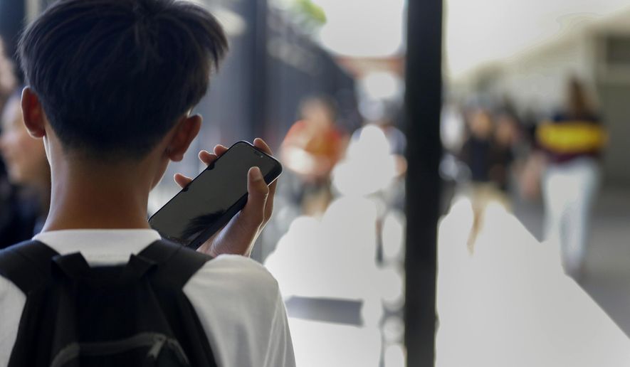 A student uses their cellphone after unlocking the pouch that secures it from use during the school day at Bayside Academy, Aug. 16, 2024, in San Mateo, Calif. (Lea Suzuki/San Francisco Chronicle via AP) ** FILE **