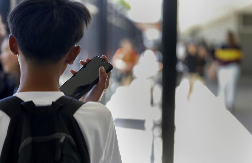 A student uses their cellphone after unlocking the pouch that secures it from use during the school day at Bayside Academy, Aug. 16, 2024, in San Mateo, Calif. (Lea Suzuki/San Francisco Chronicle via AP) ** FILE **