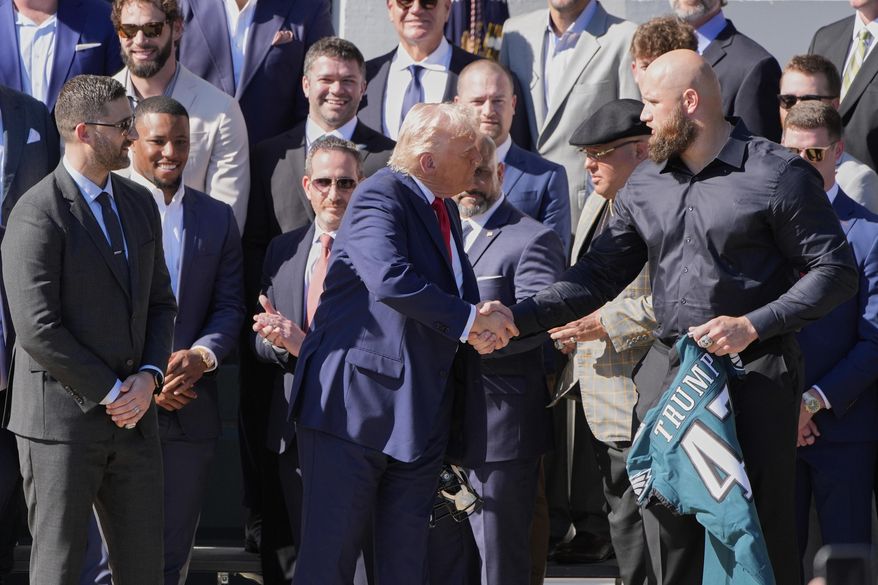 President Donald Trump, left, shakes the hand of Philadelphia Eagles NFL football player Lane Johnson as Johnson presents Trump with a jersey during a ceremony welcoming the Super Bowl champion team to the South Lawn of the White House, Monday, April 28, 2025, in Washington. (AP Photo/Alex Brandon)