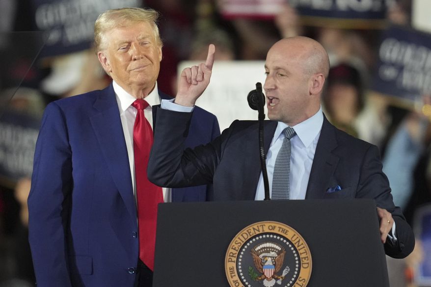 President Donald Trump listens as White House deputy chief of staff for policy Stephen Miller speaks on his first 100 days at Macomb County Community College Sports Expo Center, Tuesday, April 29, 2025, in Warren, Mich. (AP Photo/Paul Sancya)