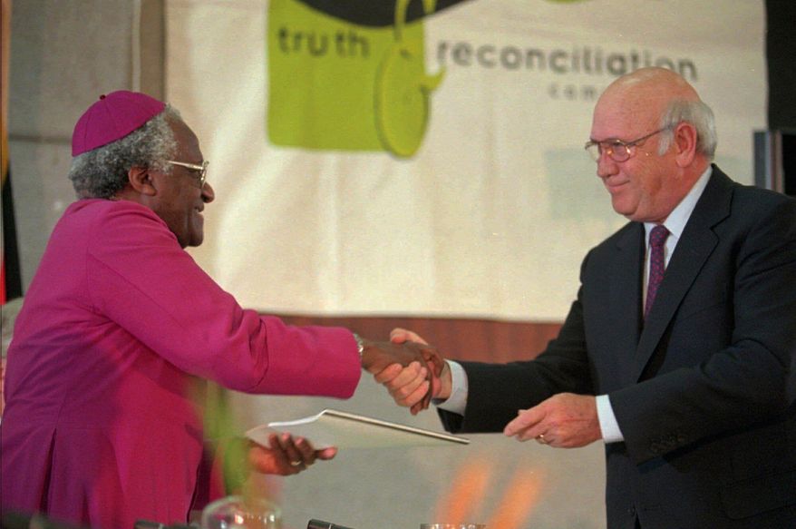 FILE - National Party leader F.W. de Klerk, right, hands over the National Party's 30-page submission to the Truth and Reconciliation Commission to the chairman Archbishop Desmond Tutu in Cape Town, Aug. 21 1996. (AP Photo/Sasa Kralj, File)