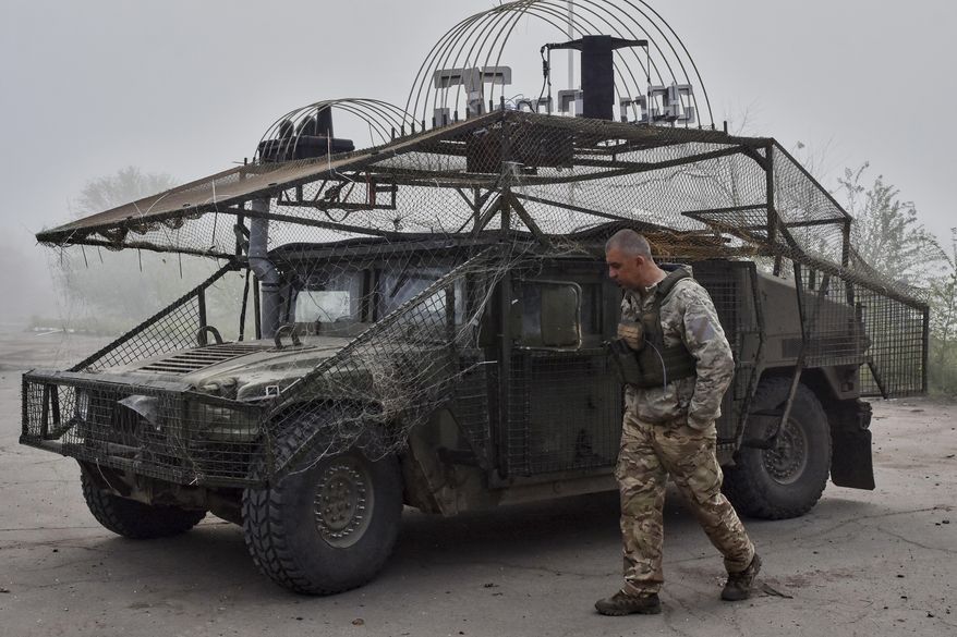 In this photo provided by Ukraine's 65th Mechanized Brigade press service, a Ukrainian soldier passes by an armoured Hummer vehicle equipped with an anti-drone net on the frontline in the Zaporizhzhia region, Ukraine, Monday, May 5, 2025. (Andriy Andriyenko/Ukraine's 65th Mechanized Brigade via AP)