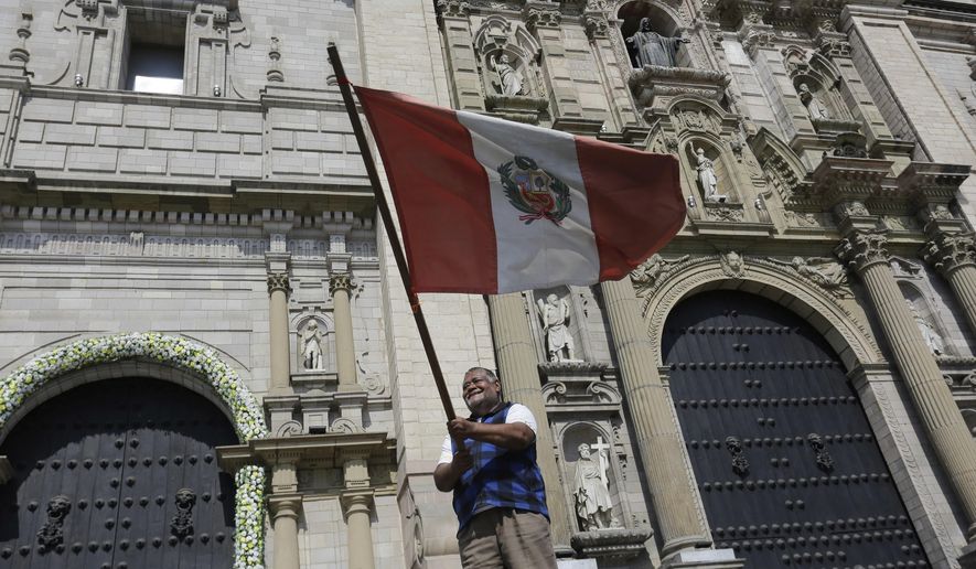 A man waves a Peruvian flag in front of the Cathedral after Cardinal Robert Prevost was elected as the new pope taking the name Leo XIV, in Lima, Peru, Thursday, May 8, 2025. (AP Photo/Cesar Zamalloa)
