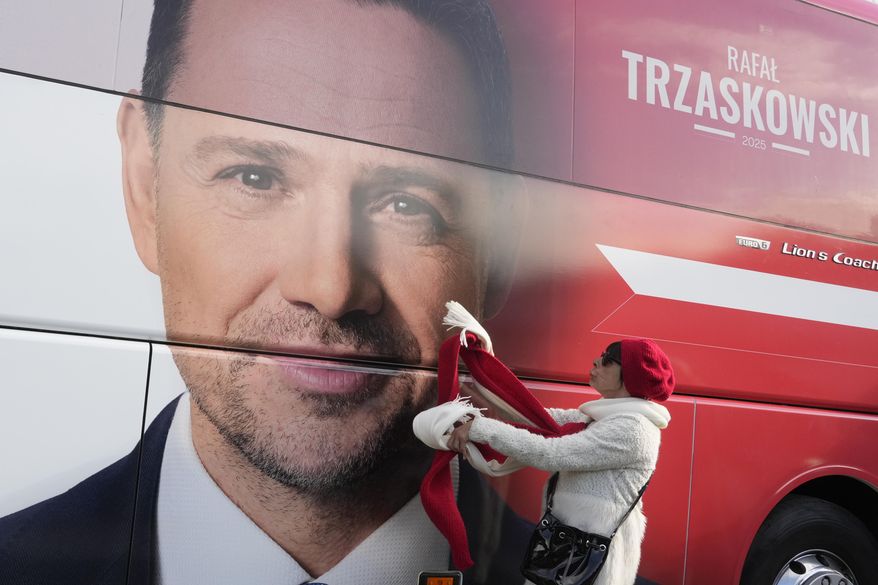 A woman stands next to a campaign poster of Warsaw Mayor Rafał Trzaskowski, a liberal candidate in Poland's presidential election, in Lodz, Poland, Friday, May 9, 2025. (AP Photo/Czarek Sokolowski)
