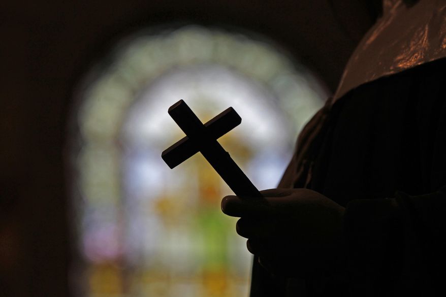 A silhouette of a crucifix and a stained glass window is seen inside a Catholic Church in New Orleans, Dec. 1, 2012. (AP Photo/Gerald Herbert, File)