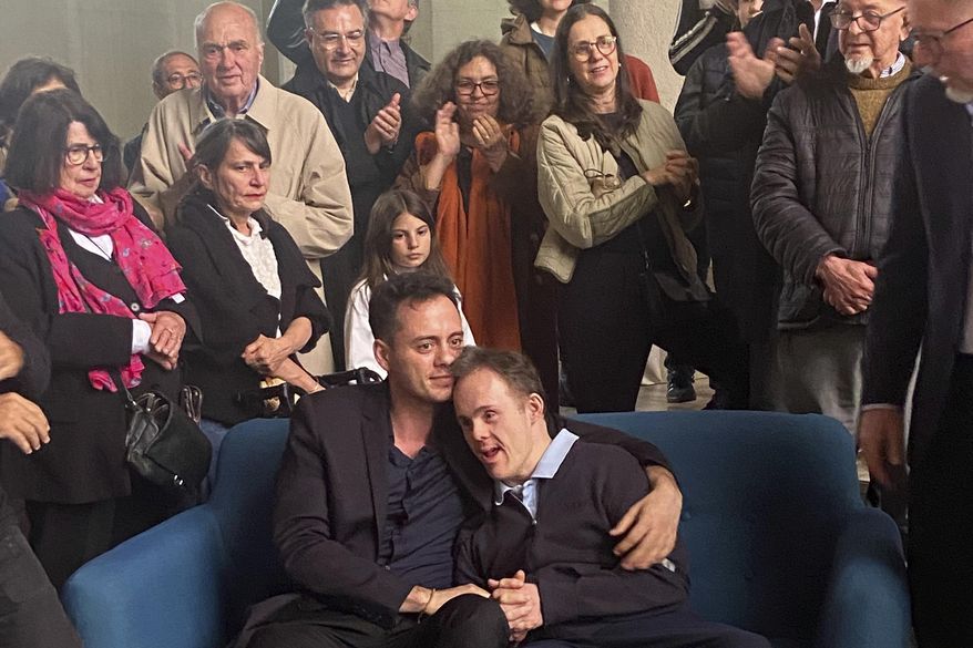 Brazilian photographer and environmentalist Sebastiao Salgado's son Rodrigo Salgado, sitting center right, with family member Flavio Salgado, pose during Rodrigo Salgado's exhibition, Saturday, May 24, 2025 in Reims, eastern France, one day after Sebastiao Salgado died at 81 from leukemia . (Sarah Heymann via AP)
