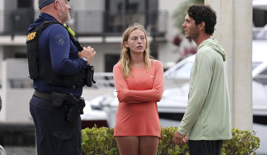 Marisa Toomsen, center, and Bret Triano, who live on their boat, talk to Fort Lauderdale police after helping rescue a man from a boat explosion near the Fort Lauderdale Yacht Club on Monday, May 26, 2025, in Fort Lauderdale, Fla. (Carline Jean/South Florida Sun Sentinel via AP)