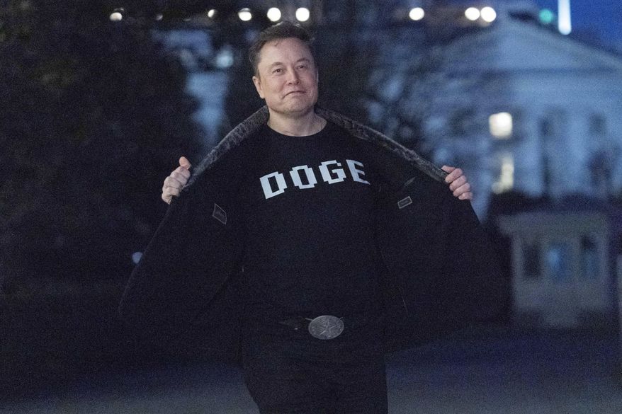 Elon Musk flashes his t-shirt that reads "DOGE" to the media as he walks on South Lawn of the White House, in Washington, March 9, 2025. (AP Photo/Jose Luis Magana, File)