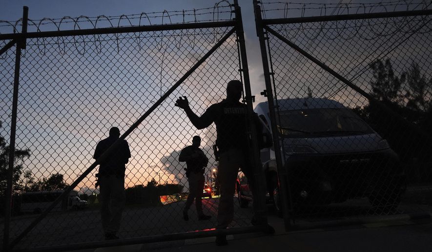 Krome Detention Center officers man an entrance gate as people hold a vigil outside to recognize those who have died in U.S. Immigration and Customs Enforcement custody, as well as those affected by mass deportations, Saturday, May 24, 2025, in Miami. (AP Photo/Rebecca Blackwell)