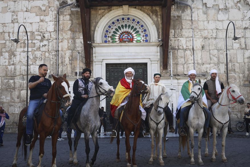 Pilgrims, including three from Spain, pose with their horses outside the Souq al-Hamidiyah market during their months-long horseback journey from Spain to Saudi Arabia to perform the Hajj, in Damascus, Syria, April 21, 2025. (AP Photo/Omar Albam)