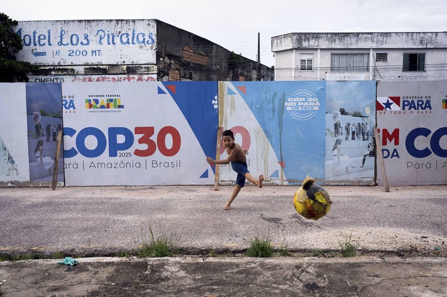 FILE - A boy kicks a soccer ball near signage for the COP30 U.N. Climate Conference in Belem, Brazil, March 23, 2025. (AP Photo/Jorge Saenz, File)