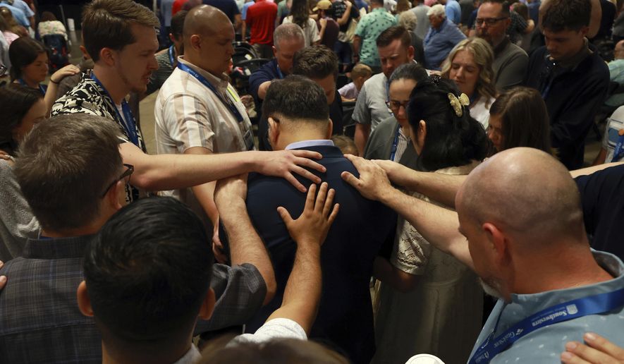 Messengers attending the Southern Baptist Convention lay on hands and pray over missionaries during the 2025 SBC Annual Meeting, Tuesday, June 10, 2025, in Dallas. (AP Photo/Richard W. Rodriguez)