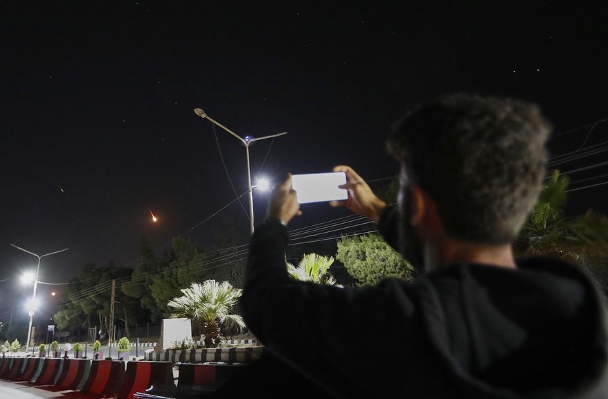 A Syrian man takes pictures with his mobile phone of Iranian missiles on their way toward Israel, as they pass over Damascus airspace, Syria, Friday, June 13, 2025. (AP Photo/Omar Sanadiki)