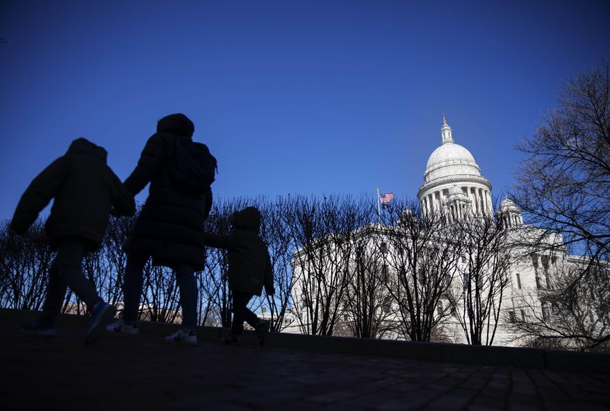 Pedestrians walk past the Rhode Island Statehouse on March 1, 2020, in Providence, R.I. (AP Photo/David Goldman, File)
