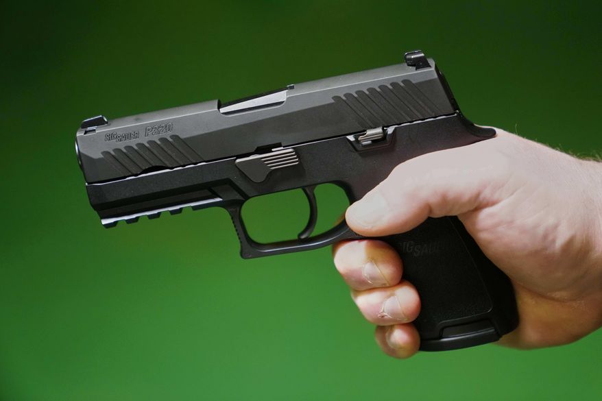 A Sig Sauer P320 handgun is held by a Maine gun shop owner, Tuesday, June 17, 2025. (AP Photo/Robert F. Bukaty)