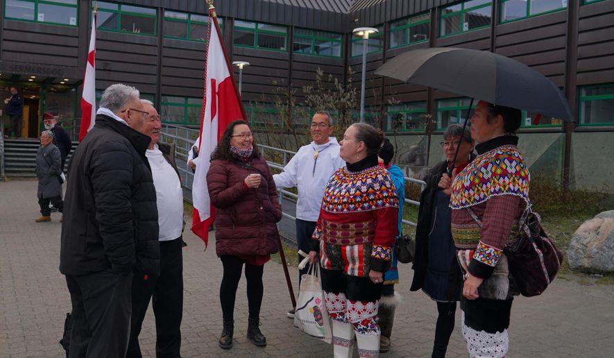 Locals wearing a traditional clothing made of pearl collar and seal hides gather in front of the town hall on the National Day in Nuuk, Greenland. (AP Photo/Kwiyeon Ha)
