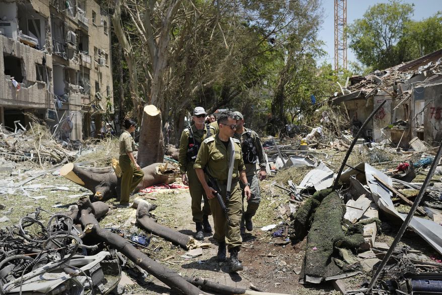 Israeli soldiers inspect the site struck by a direct missile strike launched from Iran in Tel Aviv, Israel, on Sunday, June 22, 2025. (AP Photo/Bernat Armangue)