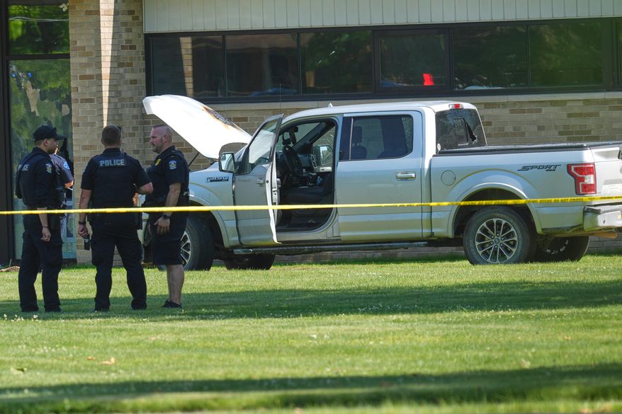 Police walk by an idle vehicle near CrossPointe Community Church in Wayne, Mich., Sunday, June 23, 2025. (AP Photo/Paul Sancya)
